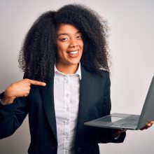 young-african-american-business-woman-with-afro-hair-using-computer-laptop-from-job-with-surprise-face-pointing-finger-himself